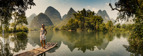 Girl standing on a raft on a Yalong River with beautiful scenery of  limestone peaks, Yangshuo, China