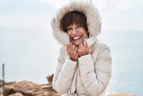 Middle age woman smiling confident freezing at seaside