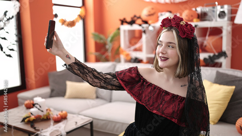Tableau sur toile Young blonde woman wearing katrina costume making selfie by smartphone at home
