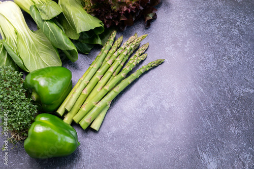 Flatly Assortment Of Fresh Organic Home Grown Green Vegetables On Gray Granite Table. Asparagus Plant, Bell Pepper, Bok Choy, Red Leaf Lettuce, Bittercresses. Healthy bio food.Horizontal, copy space. photo