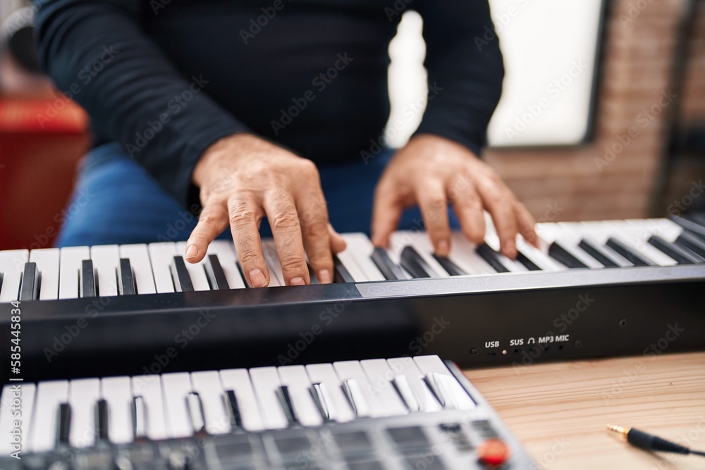 Obraz premium Middle age grey-haired man musician playing piano at music studio