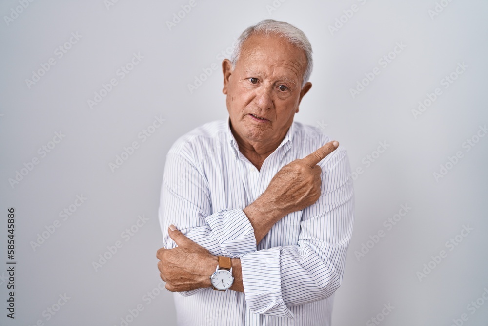Senior man with grey hair standing over isolated background pointing with hand finger to the side showing advertisement, serious and calm face Senior man with grey hair standing over isolated background pointing with hand finger to the side showing advertisement, serious and calm face