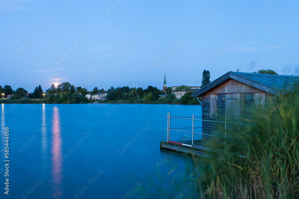 Zehdenick lake with houses at night illuminated with full moon in Brandenburg, Germany