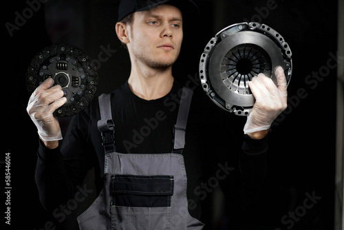 male auto mechanic with a clutch kit in his hands, replacing the clutch disc.