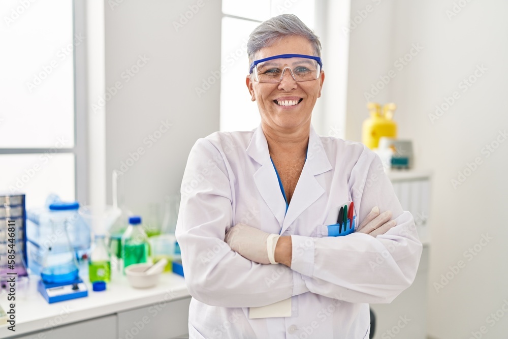 Middle age woman wearing scientist uniform standing with arms crossed gesture at laboratory Middle age woman wearing scientist uniform standing with arms crossed gesture at laboratory