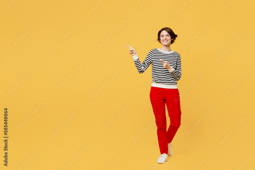 Full body smiling young woman wear casual black and white shirt pointing finger aside indicate on workspace area copy space mock up isolated on plain yellow color background studio. Lifestyle concept. Full body smiling young woman wear casual black and white shirt pointing finger aside indicate on workspace area copy space mock up isolated on plain yellow color background studio. Lifestyle concept.