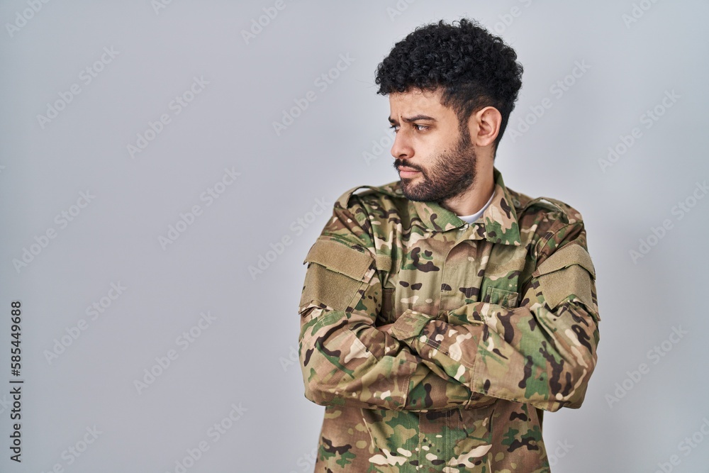 Arab man wearing camouflage army uniform looking to the side with arms crossed convinced and confident