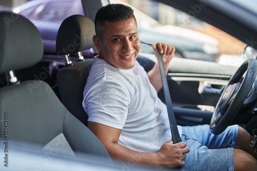 Young latin man smiling confident wearing car belt at street © Krakenimages.com