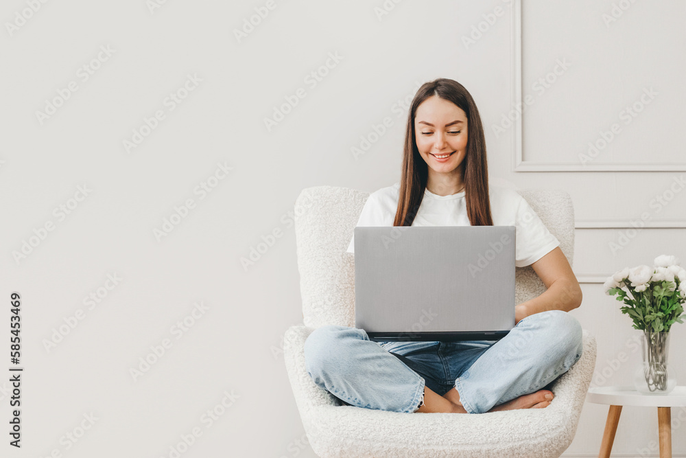 Caucasian freelancer girl sits in a chair uses a laptop and looks at the monitor screen Caucasian freelancer girl sits in a chair uses a laptop and looks at the monitor screen