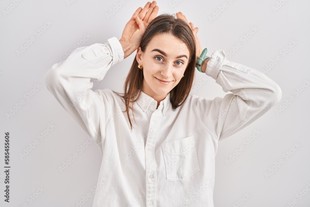 Young caucasian woman standing over isolated background doing bunny ears gesture with hands palms looking cynical and skeptical. easter rabbit concept. Young caucasian woman standing over isolated background doing bunny ears gesture with hands palms looking cynical and skeptical. easter rabbit concept.