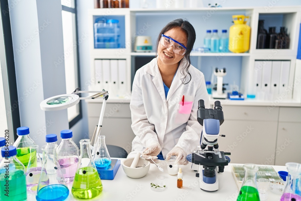 Young chinese woman wearing scientist uniform working at laboratory