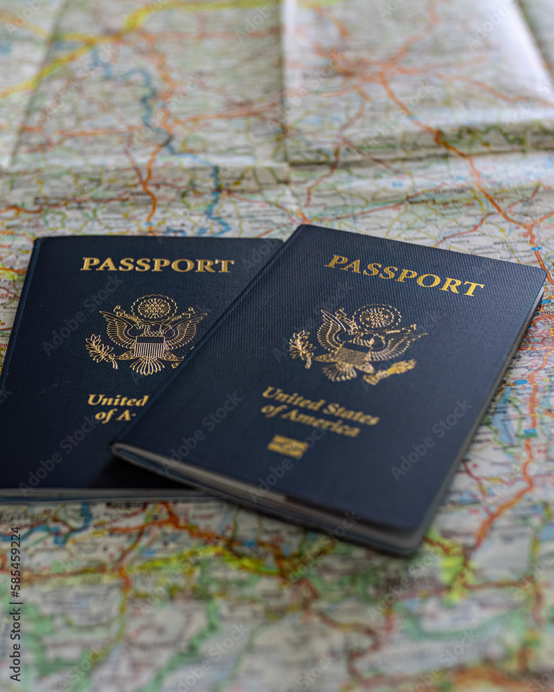 two US American passports laying on large road map of foreign country close-up two US American passports laying on large road map of foreign country close-up