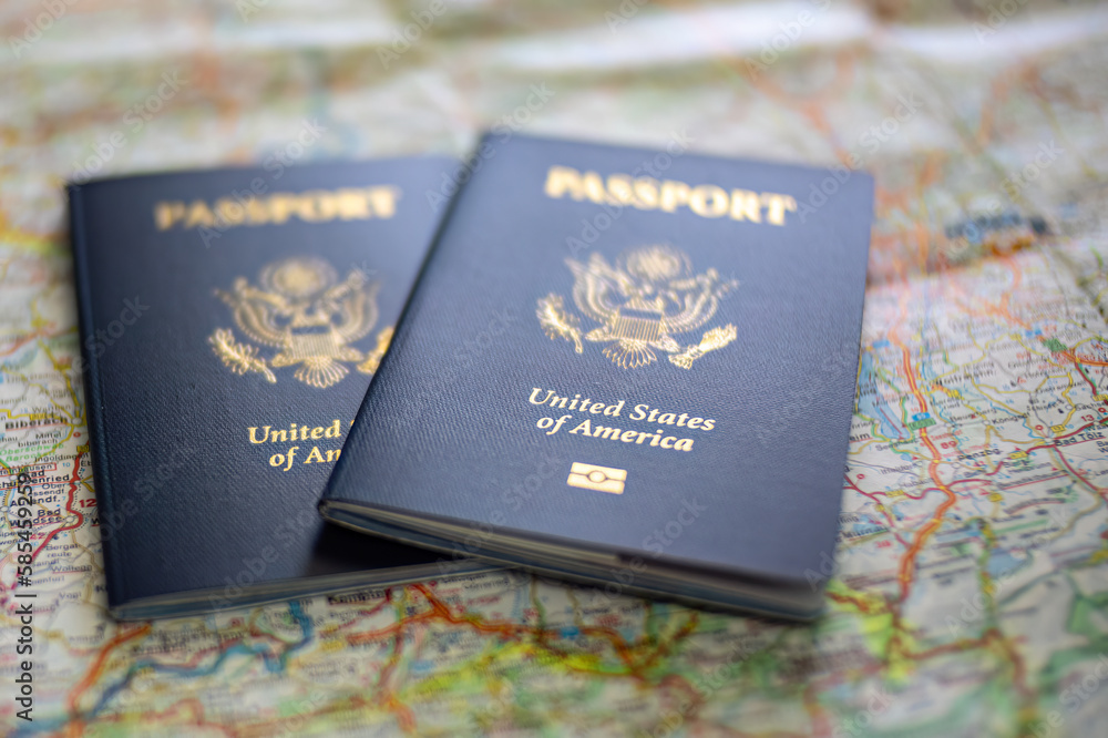 two US American passports laying on large road map of foreign country close-up two US American passports laying on large road map of foreign country close-up