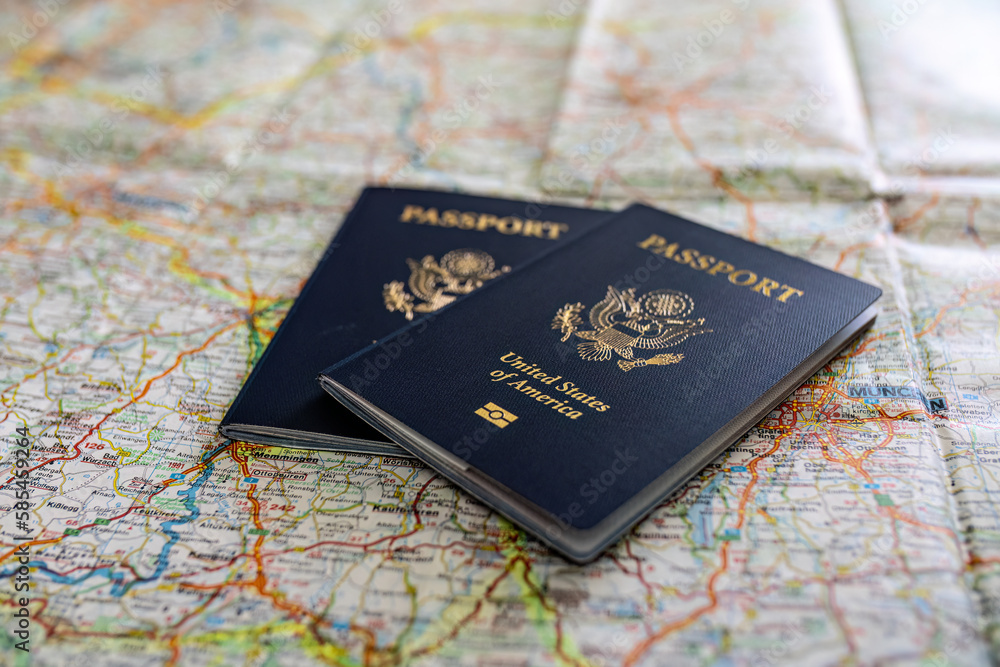 two US American passports laying on large road map of foreign country close-up two US American passports laying on large road map of foreign country close-up