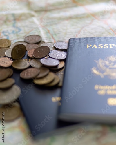 two US American passports laying on large road map of foreign country close-up with foreign currency coins falling onto pile of money photo