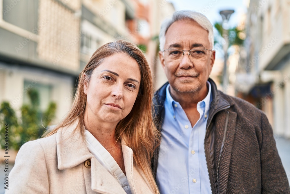 Middle age man and woman couple standing together with relaxed expression at street