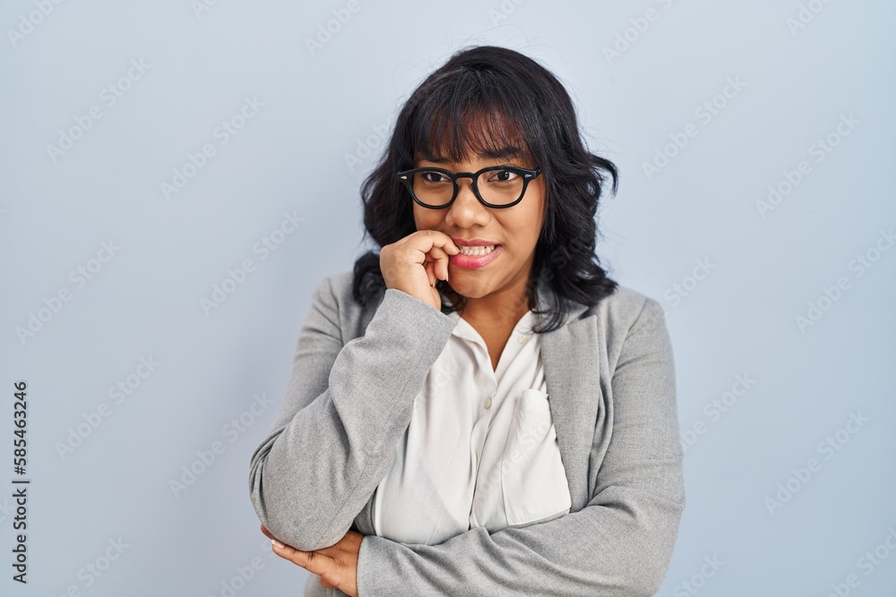Hispanic woman standing over isolated background looking stressed and nervous with hands on mouth biting nails. anxiety problem. Hispanic woman standing over isolated background looking stressed and nervous with hands on mouth biting nails. anxiety problem.