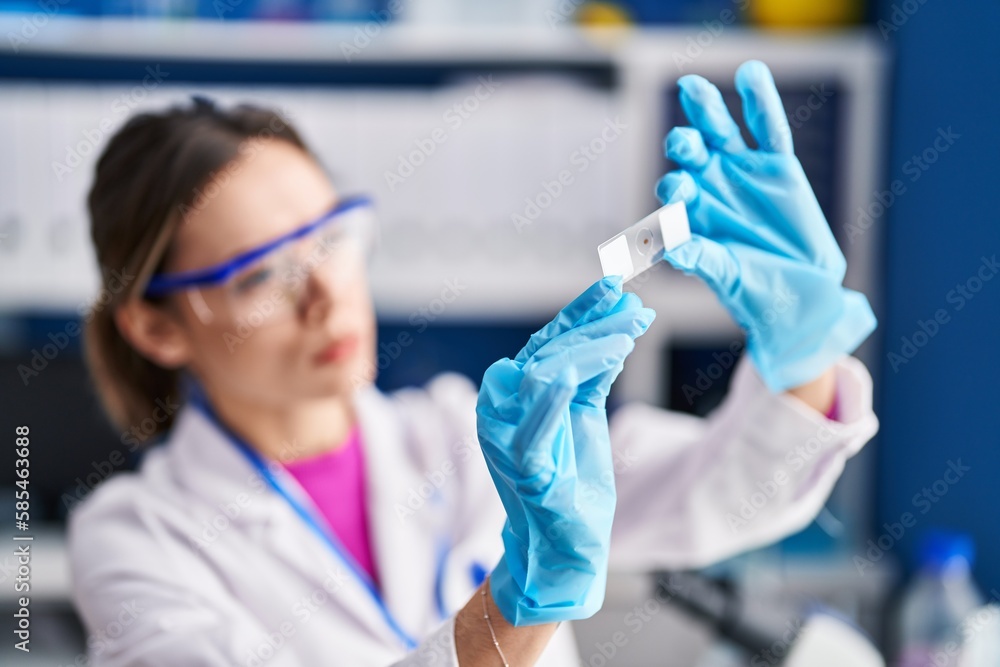 Young beautiful hispanic woman scientist looking sample at laboratory Young beautiful hispanic woman scientist looking sample at laboratory