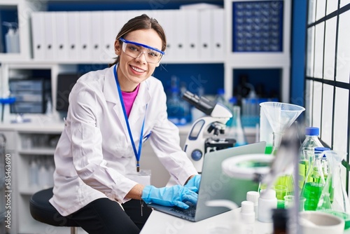 Young beautiful hispanic woman scientist smiling confident using laptop at laboratory