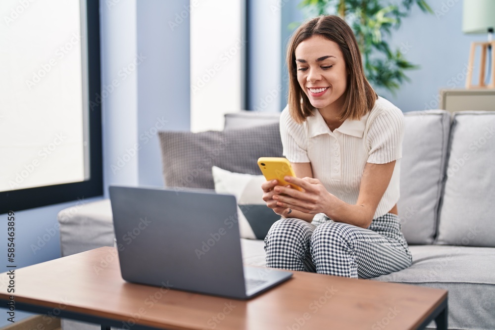 Young beautiful hispanic woman using smartphone and laptop at home Young beautiful hispanic woman using smartphone and laptop at home