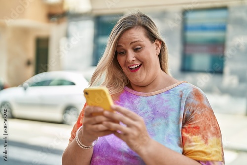 Young woman smiling confident using smartphone at street