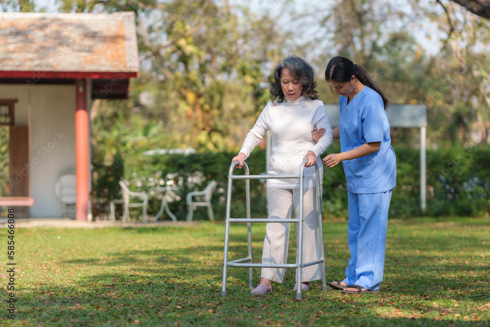 Asian nurse or a female physiotherapist is helping an elderly woman patient use a walker to learn to walk. Asian nurse or a female physiotherapist is helping an elderly woman patient use a walker to learn to walk.