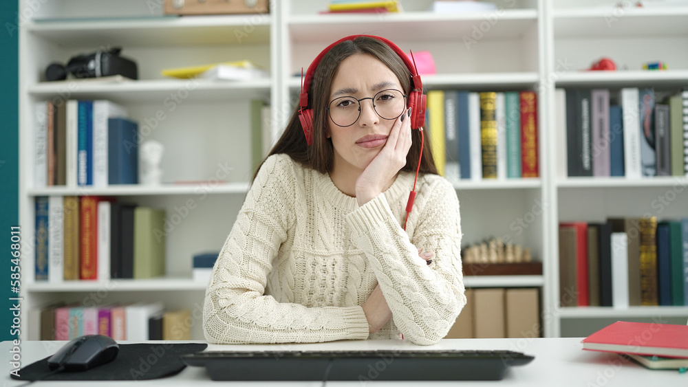 Young beautiful hispanic woman student using computer and headphones at library university Young beautiful hispanic woman student using computer and headphones at library university