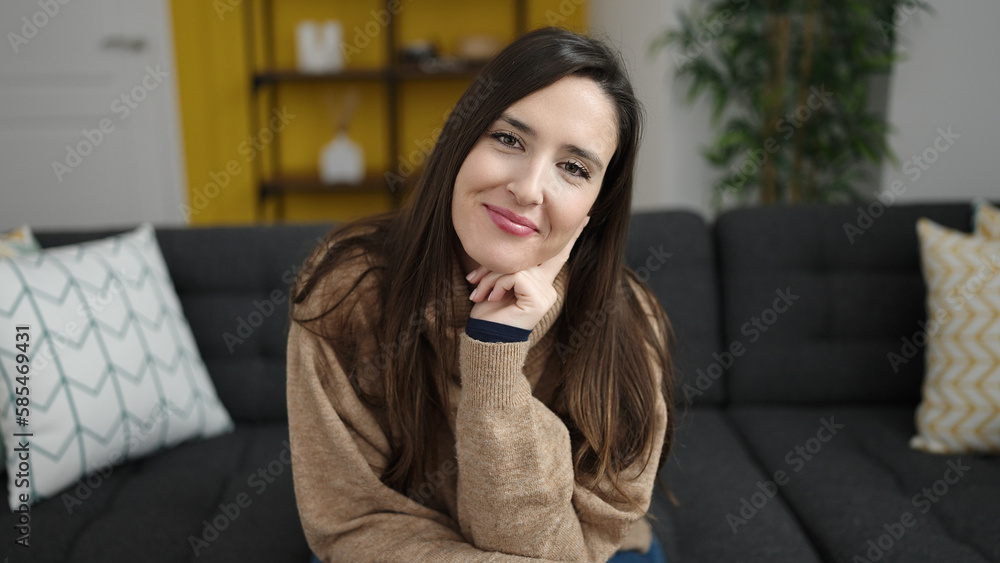 Fototapeta premium Beautiful hispanic woman smiling confident sitting on sofa at home