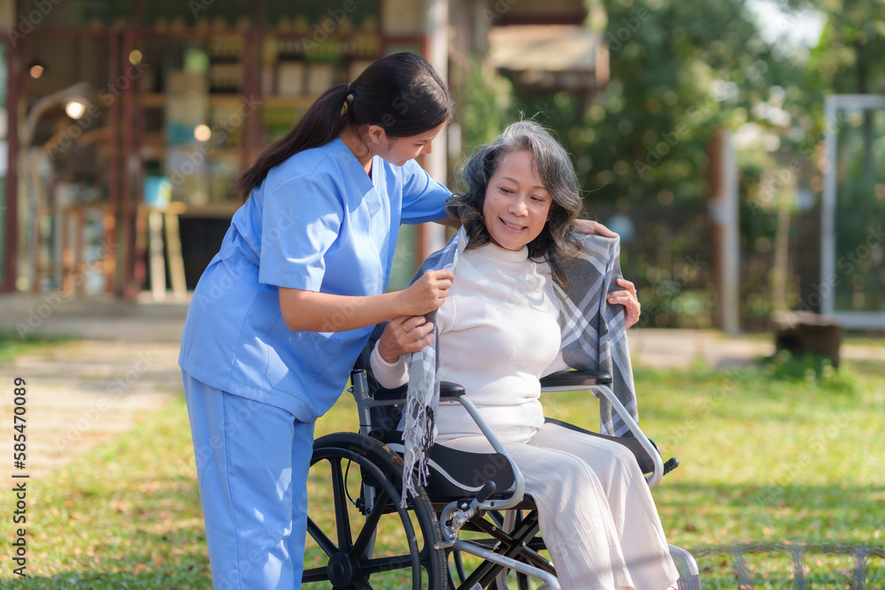 Asian nurse or physiotherapist caring for elderly woman sitting wheelchair