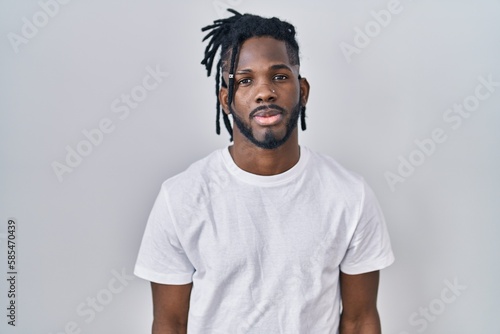 Canvas-taulu African man with dreadlocks wearing casual t shirt over white background relaxed with serious expression on face