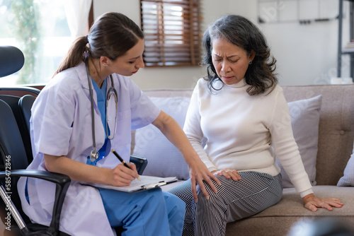 Female doctor examining the knee of an elderly Asian female patient.