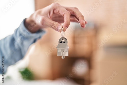 Young hispanic man holding key at new home