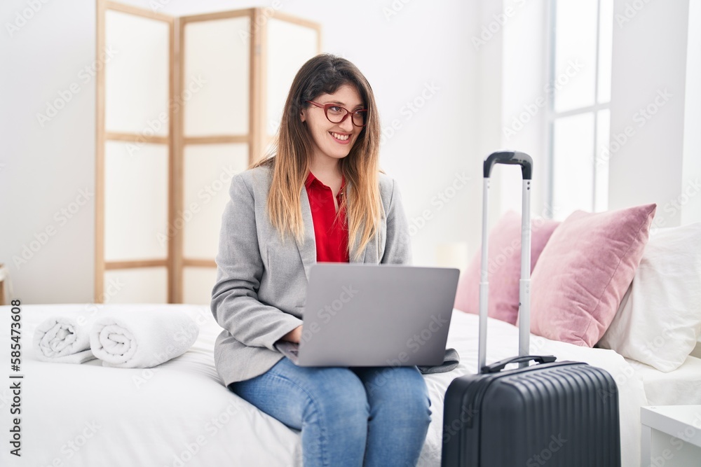 Young hispanic woman business worker using laptop sitting on bed at hotel room Young hispanic woman business worker using laptop sitting on bed at hotel room