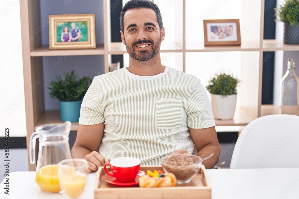 Hispanic man with beard eating breakfast with a happy and cool smile on face. lucky person. Hispanic man with beard eating breakfast with a happy and cool smile on face. lucky person.