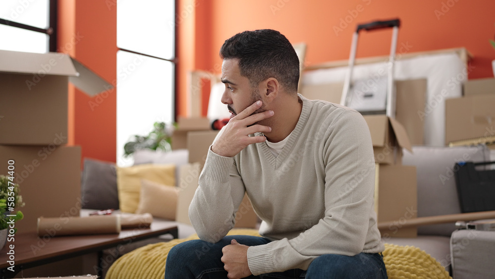Young hispanic man sitting on sofa with relaxed expression at new home Young hispanic man sitting on sofa with relaxed expression at new home