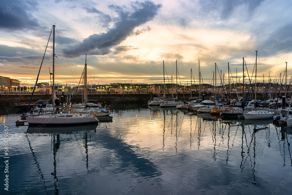 Stunning sunset in the marina of Gijon with reflections in the sea water, Asturias, Spain.