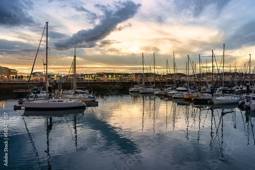Stunning sunset in the marina of Gijon with reflections in the sea water, Asturias, Spain.
