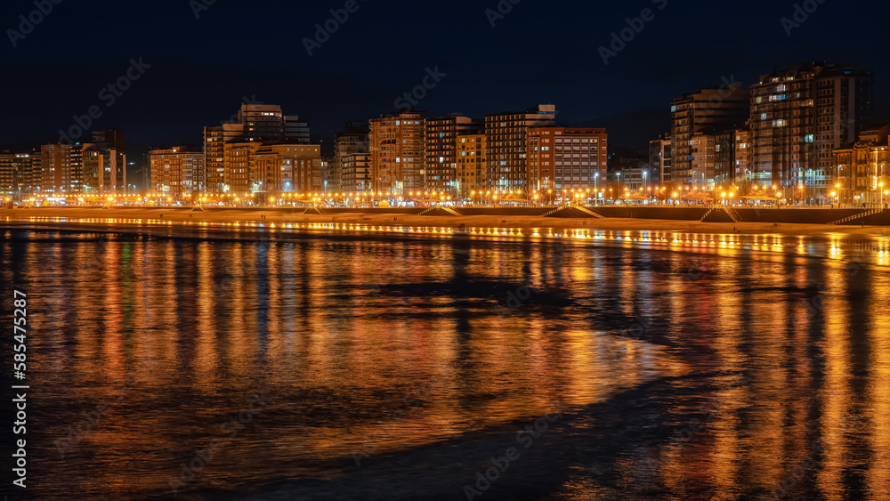 Promenade at night with reflections of lights and buildings in the sea water, Gijon, Asturias.