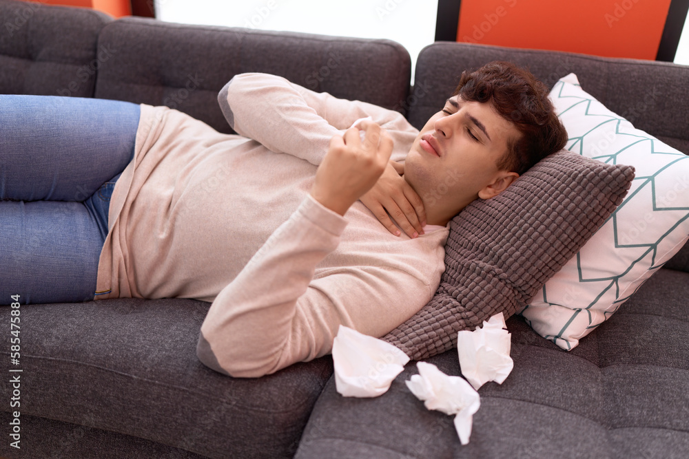 Non binary man lying on sofa using napkin at home Non binary man lying on sofa using napkin at home
