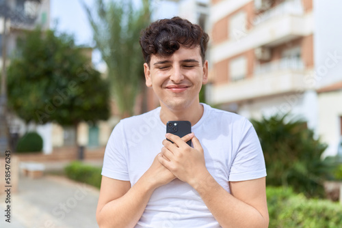 Non binary man smiling confident using smartphone at park
