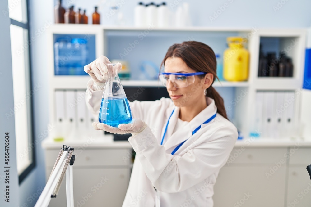 Young hispanic woman wearing scientist uniform holding test tube at laboratory Young hispanic woman wearing scientist uniform holding test tube at laboratory