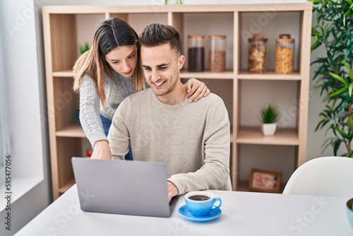 Man and woman couple hugging each other using laptop at home