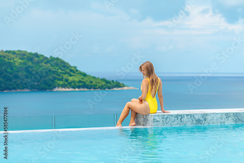 Relaxation concept - a happy female person in swimwear enjoys the refreshing water of the swimming pool at a hotel resort. Perfect summer vacation vibes.