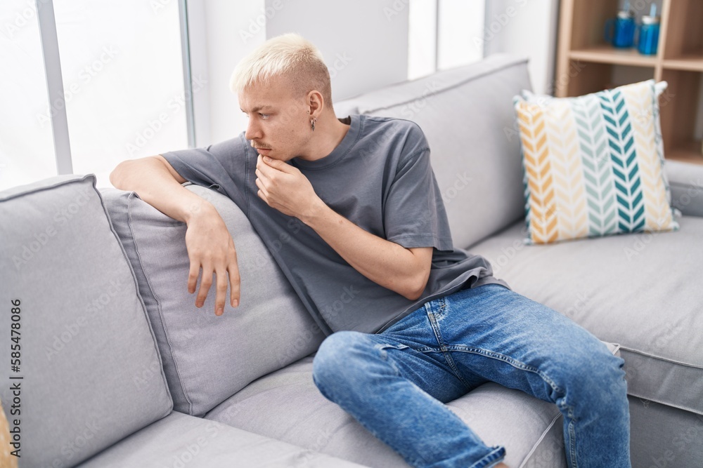 Young caucasian man sitting on sofa with serious expression at home Young caucasian man sitting on sofa with serious expression at home