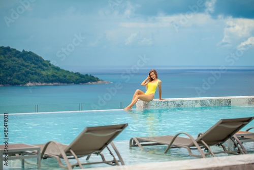 A young woman in a sexy bikini enjoys the sun and water, relaxing in the pool at a tropical resort. A picture of holiday leisure and relaxation.