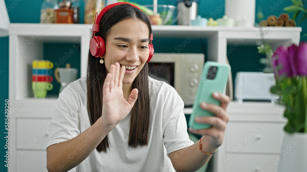 Young beautiful hispanic woman having video call sitting on table at dinning room Young beautiful hispanic woman having video call sitting on table at dinning room