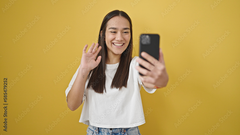 Young beautiful hispanic woman smiling having video call over isolated yellow background Young beautiful hispanic woman smiling having video call over isolated yellow background