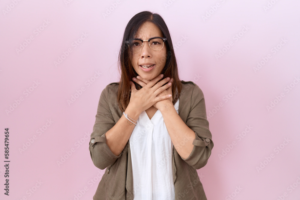 Fototapeta premium Middle age chinese woman wearing glasses over pink background shouting and suffocate because painful strangle. health problem. asphyxiate and suicide concept.