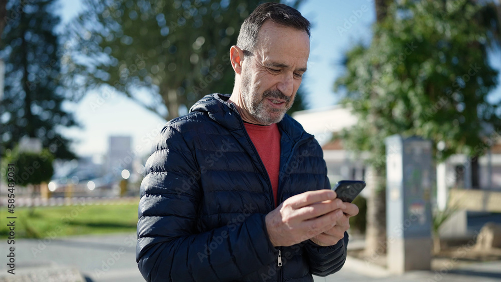 Middle age man smiling confident using smartphone at park Middle age man smiling confident using smartphone at park