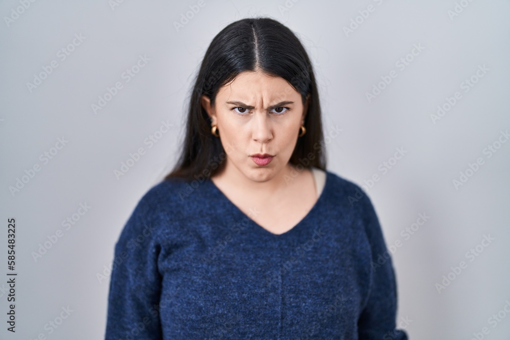 Young brunette woman standing over isolated background skeptic and nervous, frowning upset because of problem. negative person. Young brunette woman standing over isolated background skeptic and nervous, frowning upset because of problem. negative person.